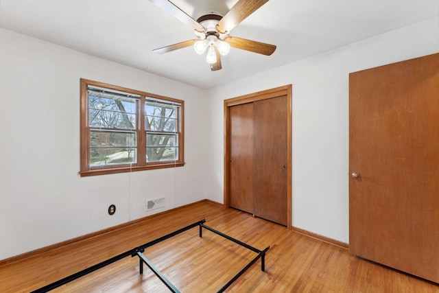 unfurnished bedroom featuring a closet, baseboards, light wood-style flooring, visible vents, and ceiling fan
