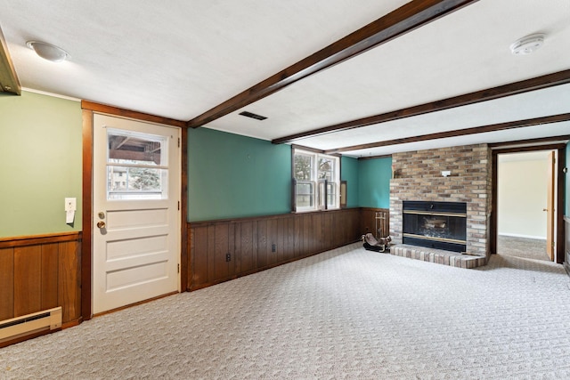 unfurnished living room featuring a brick fireplace, a baseboard radiator, wooden walls, wainscoting, and carpet flooring