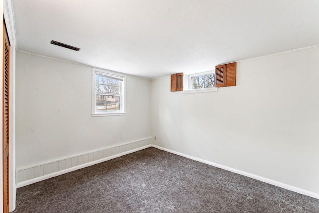 below grade area featuring dark carpet, baseboards, and visible vents