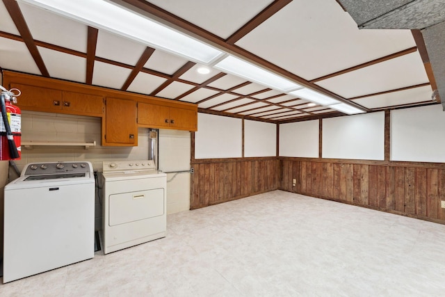 laundry area with wood walls and washer and clothes dryer