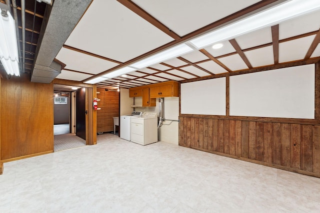 finished basement featuring wooden walls, washer and dryer, and light floors
