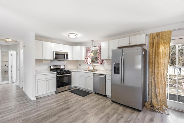 kitchen with decorative backsplash, appliances with stainless steel finishes, a sink, and light countertops