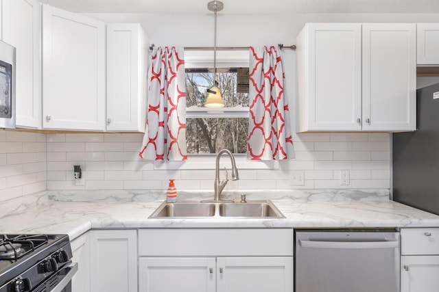 kitchen with white cabinets, a sink, hanging light fixtures, stainless steel appliances, and backsplash