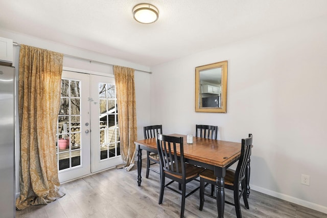 dining area with light wood-type flooring, french doors, and baseboards