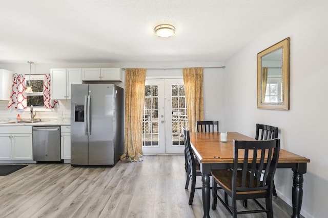 dining space featuring plenty of natural light, french doors, and light wood-type flooring