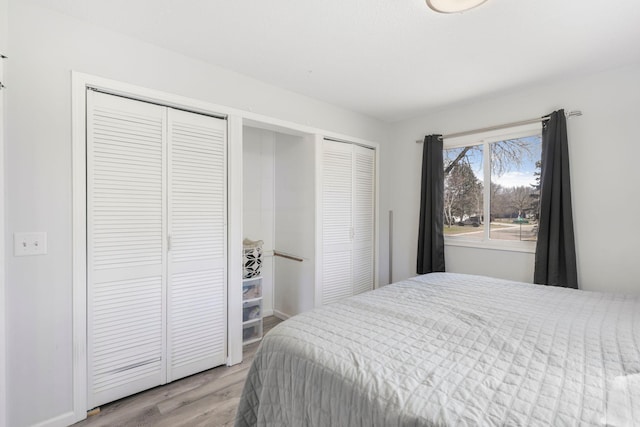 bedroom featuring two closets and light wood-style floors