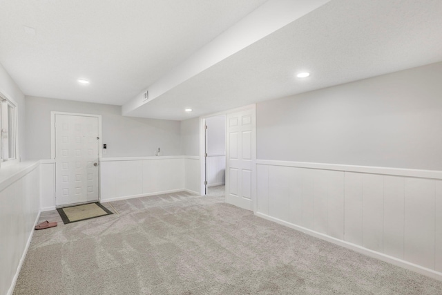 finished basement featuring recessed lighting, carpet flooring, visible vents, and a wainscoted wall