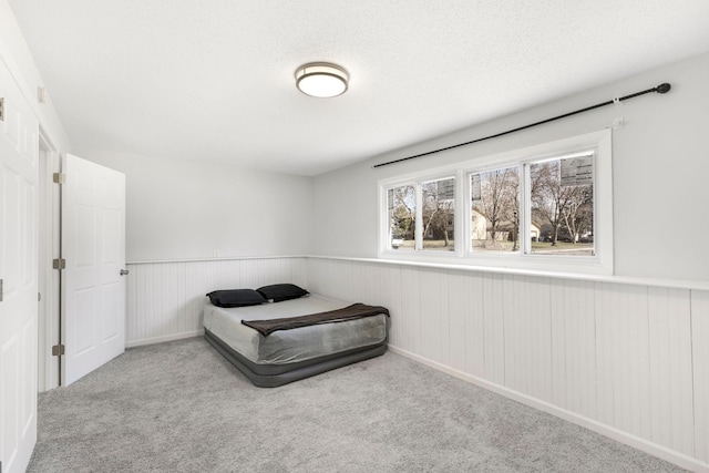 carpeted bedroom featuring wainscoting