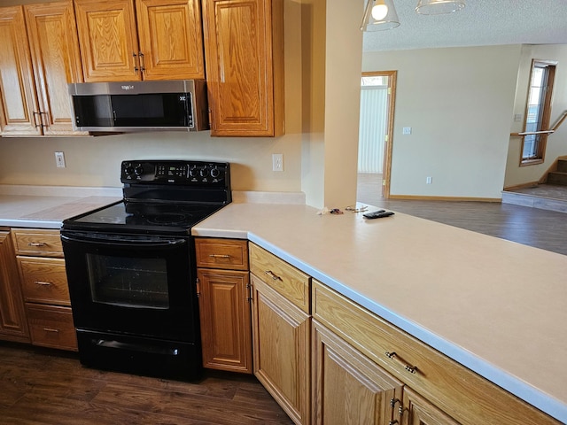 2208 10th Ave SE Unit 12, Willmar, MN 56201 - kitchen with stainless steel microwave, electric range, dark wood-type flooring, light countertops, and brown cabinets