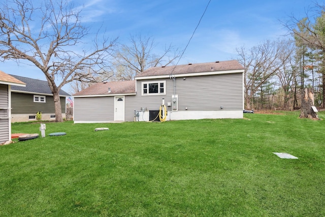 rear view of house with a lawn and roof with shingles