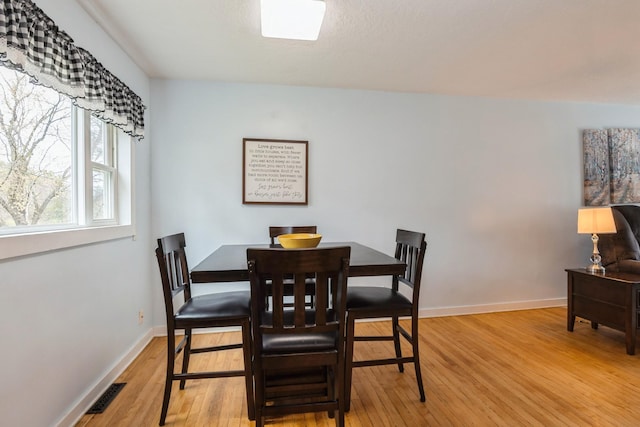 dining room with baseboards, visible vents, and wood finished floors