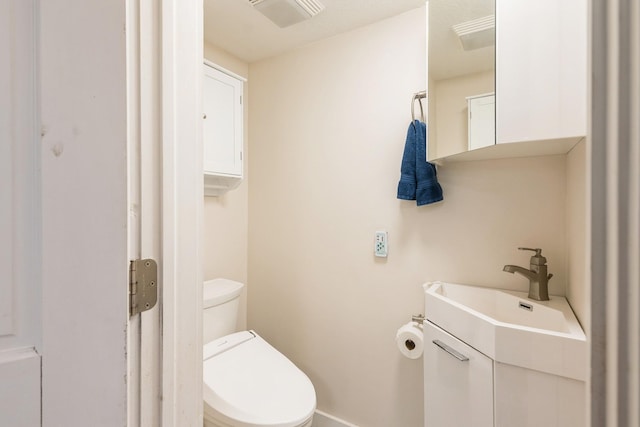 bathroom featuring baseboards, visible vents, toilet, and a sink