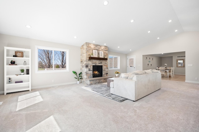 living room with light colored carpet, vaulted ceiling, a stone fireplace, and baseboards