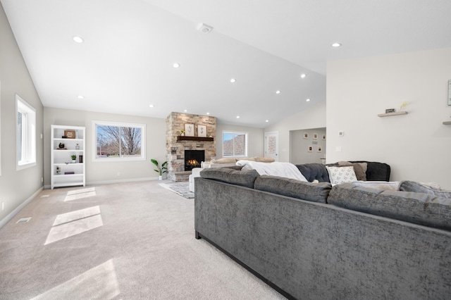 living area featuring vaulted ceiling, light carpet, a stone fireplace, and a wealth of natural light