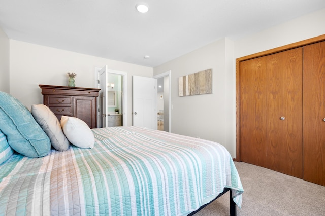carpeted bedroom with ensuite bath and a closet