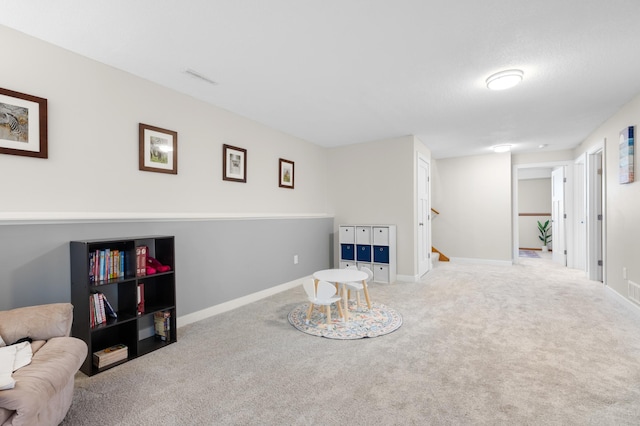 carpeted living room featuring baseboards, visible vents, and stairs