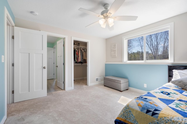 bedroom featuring visible vents, carpet, a ceiling fan, a closet, and a walk in closet