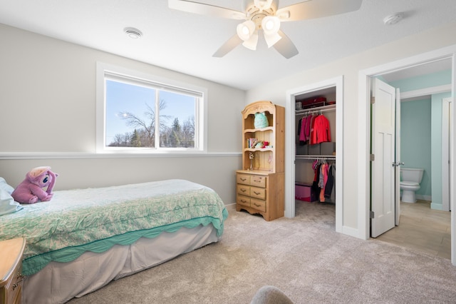 bedroom featuring a ceiling fan, a closet, a walk in closet, light colored carpet, and baseboards