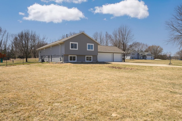 view of side of home with concrete driveway, fence, a lawn, and a garage