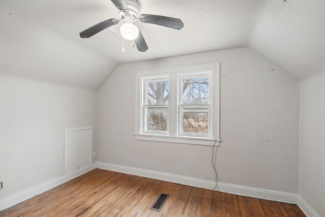 bonus room with lofted ceiling, wood finished floors, baseboards, ceiling fan, and a textured ceiling