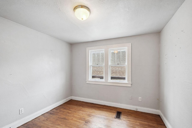 empty room featuring baseboards, wood finished floors, and a textured ceiling