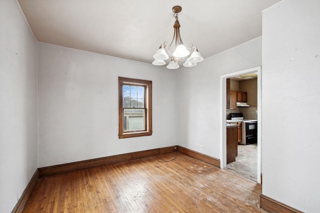 unfurnished room featuring a chandelier, light wood finished floors, and baseboards