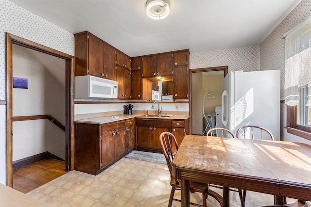100 Stark Rd, Harris, MN 55032 - kitchen with wallpapered walls, white appliances, washer and clothes dryer, a sink, and light countertops