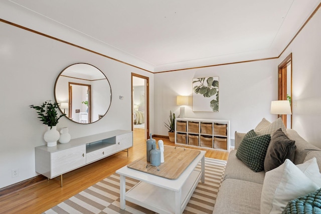 living area with wood finished floors, baseboards, and crown molding