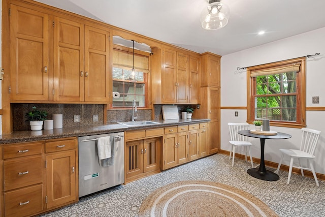 kitchen with dishwasher, a sink, brown cabinetry, tasteful backsplash, and dark countertops