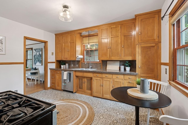 kitchen featuring dishwasher, a sink, black gas stove, backsplash, and brown cabinets