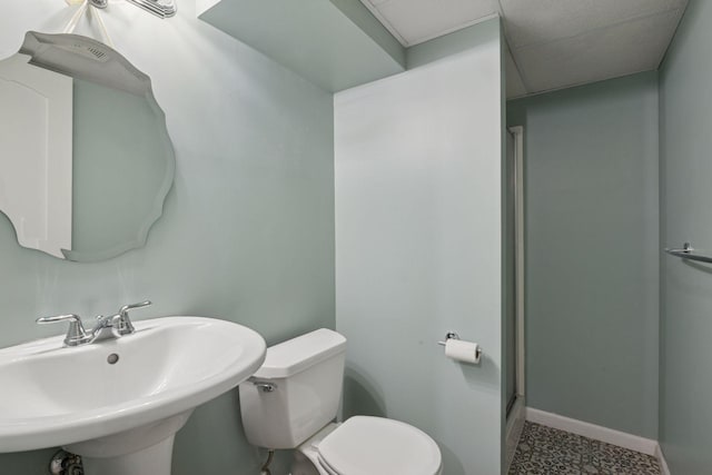 bathroom with toilet, a sink, baseboards, and a shower with door