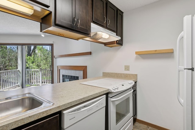 kitchen with dark brown cabinetry, a sink, a fireplace, white appliances, and light countertops