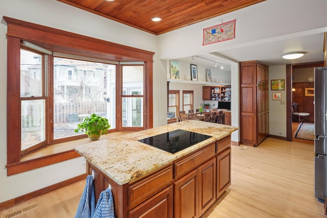 1767 Fremont Ave S, Minneapolis, MN 55403 - kitchen with black electric stovetop, light wood-type flooring, a center island, light stone counters, and brown cabinets