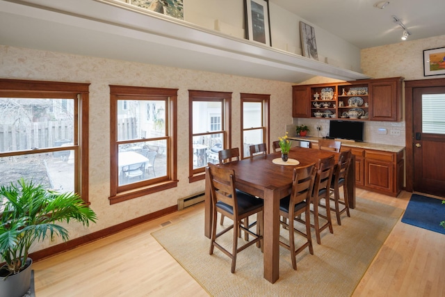 1767 Fremont Ave S, Minneapolis, MN 55403 - dining space with a baseboard heating unit, light wood-style flooring, wallpapered walls, and healthy amount of natural light