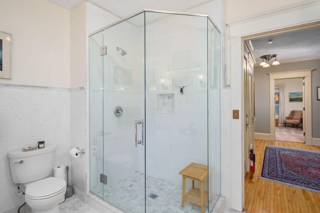 1767 Fremont Ave S, Minneapolis, MN 55403 - full bathroom featuring a shower stall, tile walls, wood finished floors, and a wainscoted wall