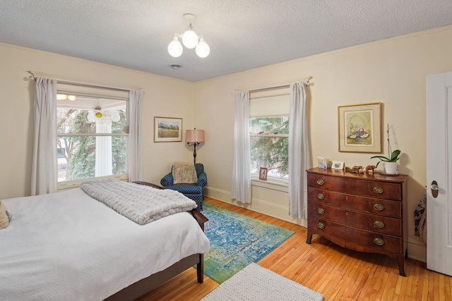 1767 Fremont Ave S, Minneapolis, MN 55403 - bedroom featuring light wood-style flooring, multiple windows, a textured ceiling, and a chandelier