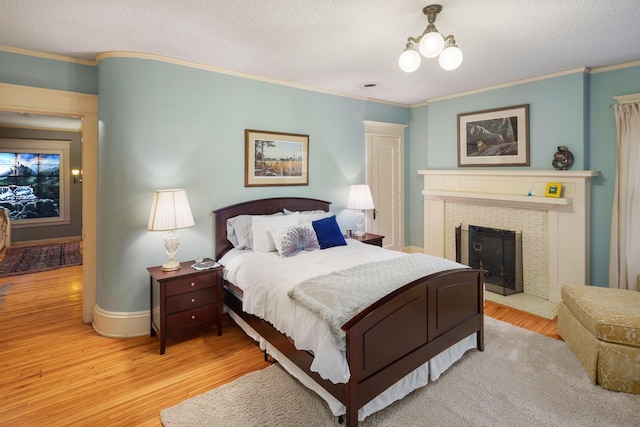 1767 Fremont Ave S, Minneapolis, MN 55403 - bedroom featuring ornamental molding, light wood finished floors, a fireplace, and a textured ceiling