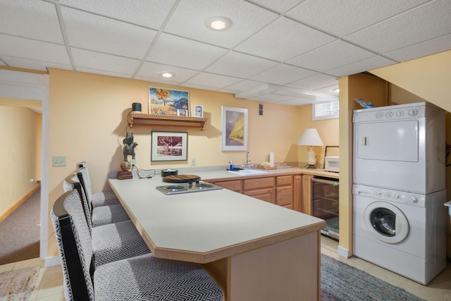 1767 Fremont Ave S, Minneapolis, MN 55403 - kitchen with beverage cooler, stacked washer / dryer, a peninsula, light countertops, and a drop ceiling