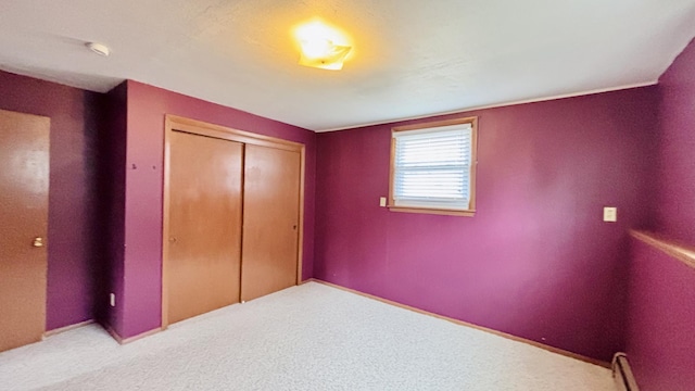 unfurnished bedroom with baseboard heating, a closet, and carpet floors