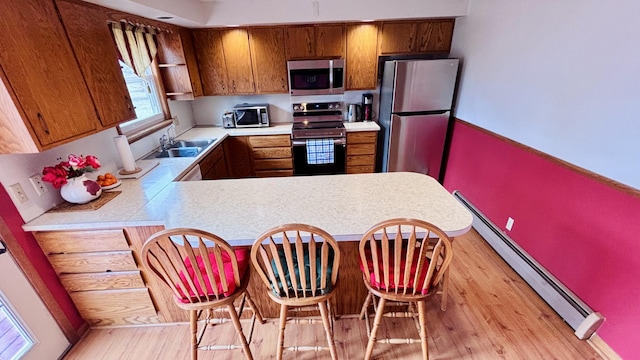 350 Lakehill Dr, Worthington, MN 56187 - kitchen with stainless steel appliances, a baseboard heating unit, light countertops, brown cabinetry, and light wood-type flooring