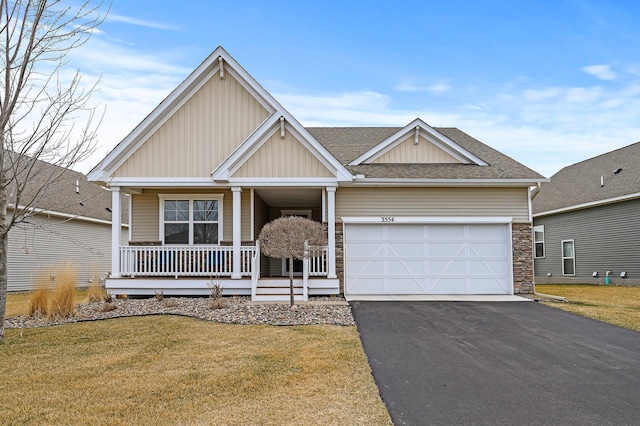 craftsman house featuring roof with shingles, driveway, a front lawn, a porch, and a garage