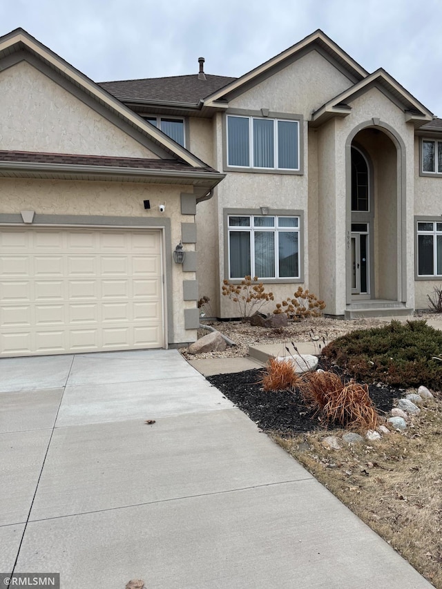 view of front of house featuring stucco siding, driveway, a shingled roof, and a garage