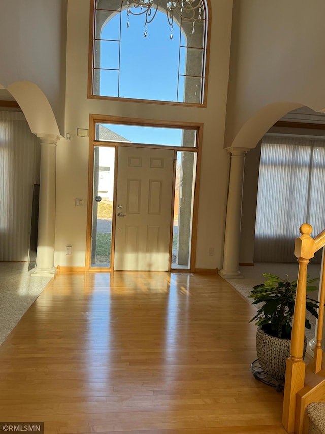 entryway featuring wood finished floors, a high ceiling, and ornate columns