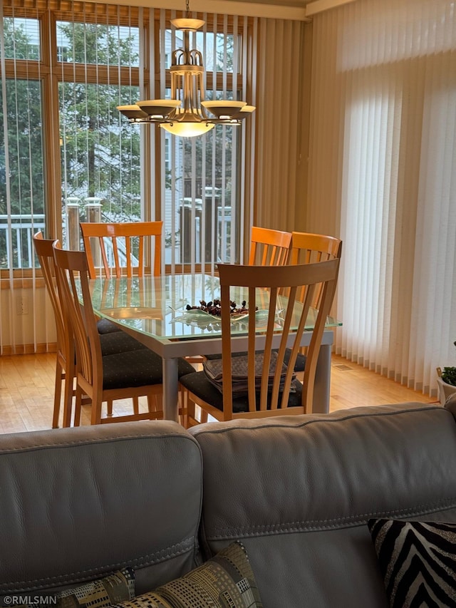 dining space featuring wood finished floors, a healthy amount of sunlight, and an inviting chandelier