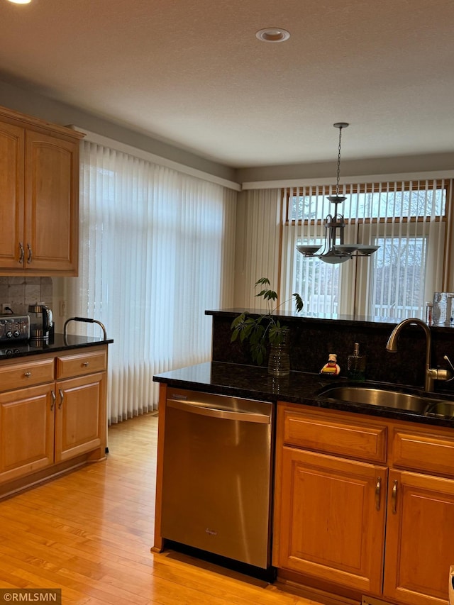 kitchen with a sink, decorative backsplash, dishwasher, light wood finished floors, and decorative light fixtures