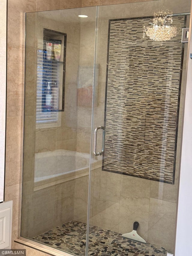 bathroom featuring a chandelier and a stall shower