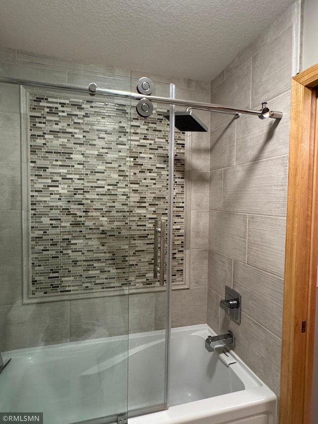 full bathroom featuring a textured ceiling and bath / shower combo with glass door