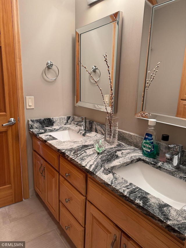 full bathroom with double vanity, tile patterned flooring, and a sink