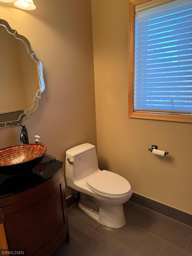 bathroom with baseboards, vanity, and toilet