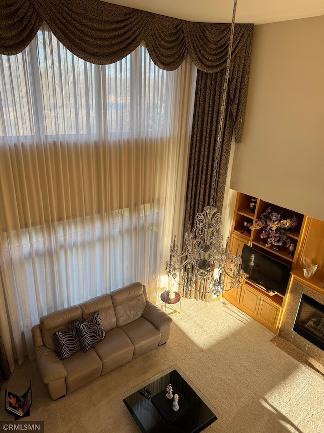carpeted living room featuring a tile fireplace, a healthy amount of sunlight, and built in features